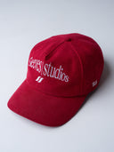 Red corduroy cap with soft ribbed texture, curved “Sleeves Studios” front embroidery, brand icon below, SLV initials on the side, structured crown and adjustable back for custom fit