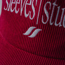 Red corduroy cap with soft ribbed texture, curved “Sleeves Studios” front embroidery, brand icon below, SLV initials on the side, structured crown and adjustable back for custom fit