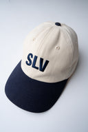white and blue cotton cap, lightweight and breathable, SLV initials embroidered above the visor, Sleeves Studios icon on back, adjustable strap for one-size fit