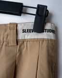 Khaki cotton baggy pants with high-waisted street fit, elastic back waistband, side and back pockets, zipper fly, and relaxed drape for everyday comfort by Sleeves Studios