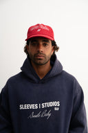 Red corduroy cap with soft ribbed texture, curved “Sleeves Studios” front embroidery, brand icon below, SLV initials on the side, structured crown and adjustable back for custom fit
