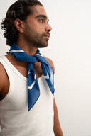 Man wearing a blue scarf around his neck against a white background - blue bandanna / headscarf  with text "tie your style baby" Sleeves Studios' branding