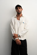Man wearing a white shirt and black pants against a plain background  - sleeves studios - white Button-up shirt - blue label - white shirt