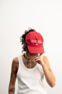 Red corduroy cap with soft ribbed texture, curved “Sleeves Studios” front embroidery, brand icon below, SLV initials on the side, structured crown and adjustable back for custom fit
