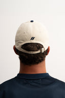 white and blue cotton cap, lightweight and breathable, SLV initials embroidered above the visor, Sleeves Studios icon on back, adjustable strap for one-size fit