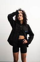 Woman wearing a black outfit with a black shirt and shorts on a white background - sleeves studios - black Button-up shirt - blue label 