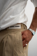 Khaki cotton baggy pants with high-waisted street fit, elastic back waistband, side and back pockets, zipper fly, and relaxed drape for everyday comfort by Sleeves Studios