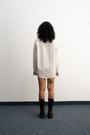 Person wearing a white oversized shirt and black boots against a plain -  - sleeves studios - white Button-up shirt - blue label - white shirtwall.