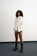 Person wearing a white shirt and black boots against a plain background - sleeves studios - white Button-up shirt - blue label - white shirt