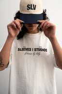 Person wearing a white t-shirt with text dream big baby and a cap